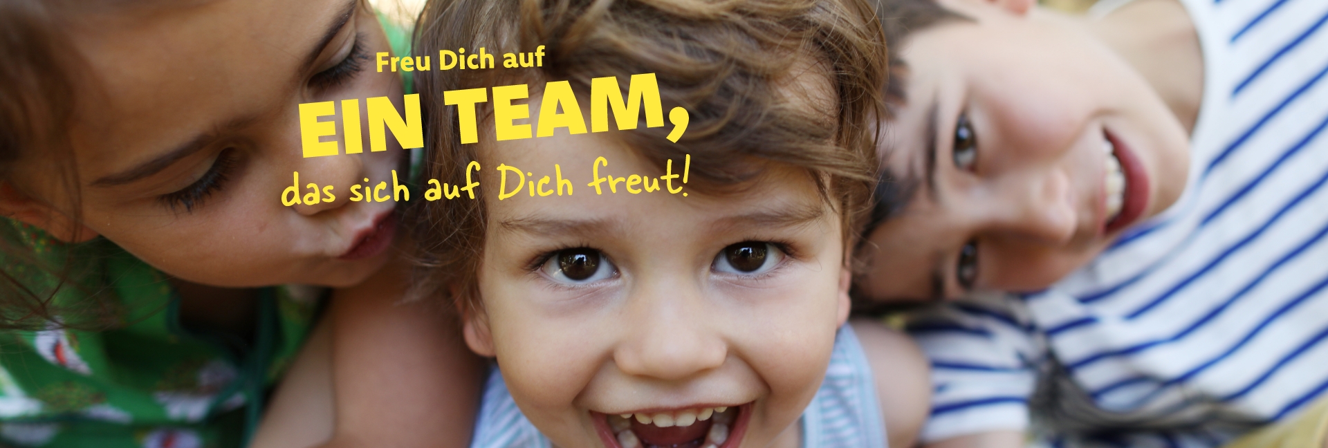 Der Junge in der Mitte des Bildes lacht in die Kamera. Die beiden anderen Kinder sind im Hintergrund. Auf dem Bild ist der Schriftzug "Freu Dich auf ein Team, das sich auf Dich freut!" abgebildet.