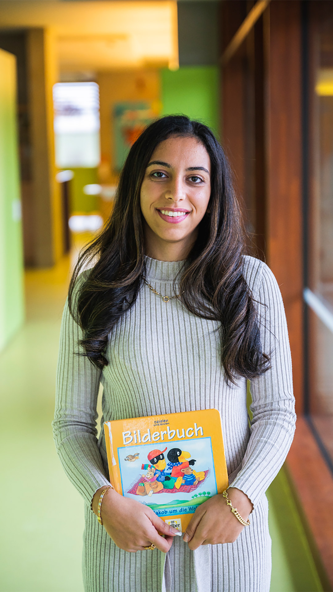 Eine Frau hält lächelnd ein Bilderbuch.