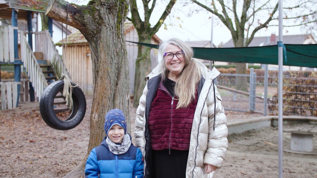 Siegunde steht mit einem Jungen draußen auf dem Spielplatz des Kindergartens.